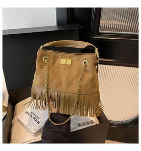Close-up of brown suede bag with tassel fringe, quilted pattern and gold turn-lock