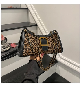Close-up of leopard print baguette bag featuring gold buckle and metal chain strap