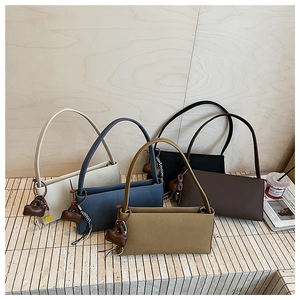 Close-up of five minimalist baguette shoulder bags in earthy tones on a stone surface