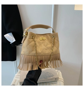 Detailed view of beige suede bag featuring diamond stitching, gold lock and fringe tassels