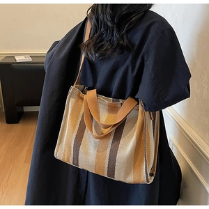 Detailed side view of large striped canvas tote bag worn by model for daily commute style