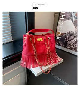 Detailed view of red suede handbag with golden twist lock and elegant fringe decor
