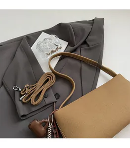Brown woven baguette bag with adjustable shoulder strap and a heart-shaped charm detail