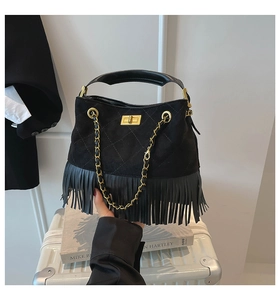 Detail view of quilted black suede bag with fringe trim, gold lock, and chain strap