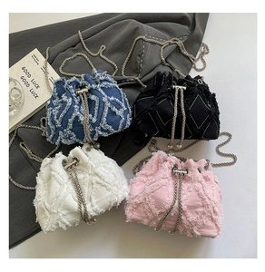 Top view of four frayed denim bucket bags in blue, black, white, and pink with chain straps
