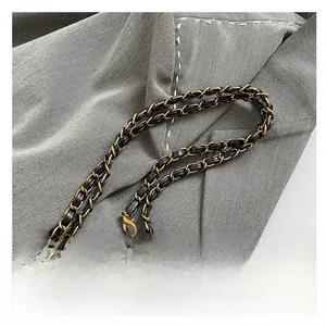 Detail of metal chain and black leather woven strap with vintage gold hardware