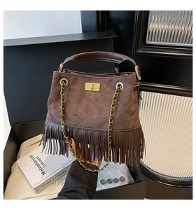 Detailed view of brown suede tassel handbag with gold chain strap and turn-lock closure