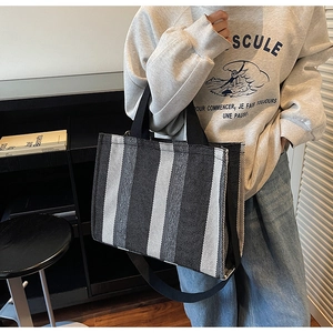 Vertical striped canvas tote bag showing top black handles and wide crossbody strap detail
