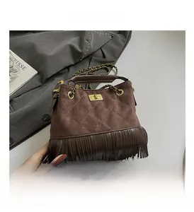 Detail of dark brown suede fringe bag with diamond stitching and gold turn-lock