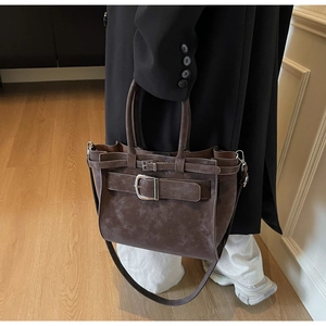 Macro view of vintage brown tote with large buckle detail and soft suede texture