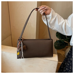 Close-up of vintage dark brown baguette bag with decorative charms and soft matte finish