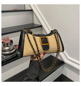 Detail of vintage beige suede baguette bag with black leather trim and gold metal buckle