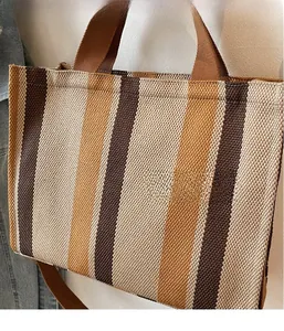 Close-up of striped canvas tote bag with brown woven handles and adjustable shoulder strap