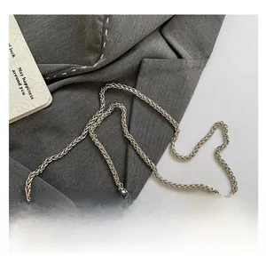 Close-up of bright silver woven metal chain strap with polished alloy finish on bag