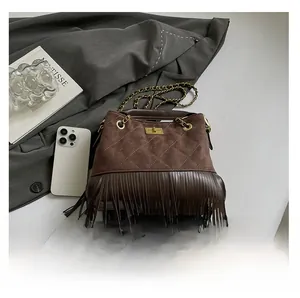 Detailed view of brown suede crossbody bag with decorative tassels and gold metal turn-lock