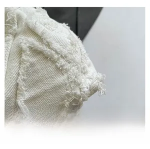 Detailed macro view of white twill denim fabric with trendy frayed edge and fringed texture