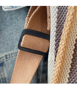 Close-up of the woven brown shoulder strap and black adjustable buckle on the tote bag