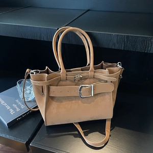 Detail view of khaki suede shoulder bag featuring decorative belt and silver metal hardware