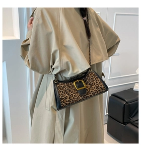 Detail of leopard print baguette bag with golden buckle on a khaki trench coat model