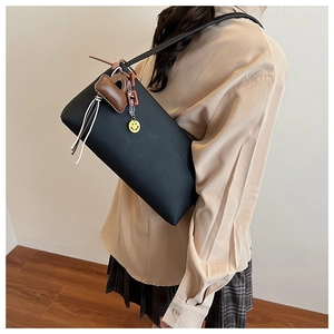 Detail of black leather underarm bag featuring a brown mini pouch and yellow smiley pendant