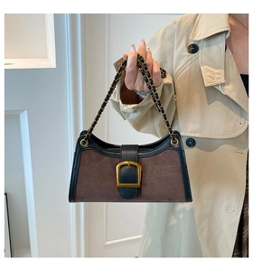 Detail of vintage brown suede baguette bag with gold buckle and chain strap