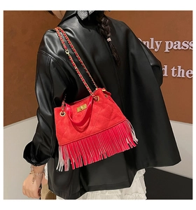 Detail of red suede tassel shoulder bag with gold chain strap worn over a black leather jacket