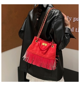 Detail of red quilted suede crossbody bag with long tassels and gold chain strap