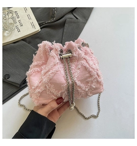 Detail of pink denim bucket bag with frayed quilted patterns and pearl chain strap