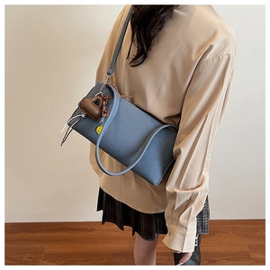 Detailed macro view of blue fabric texture handbag with cute charms on long shoulder strap
