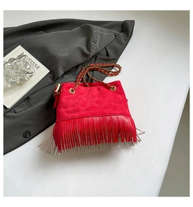 Detail of red suede bucket bag with fringe, quilted pattern and gold chain strap
