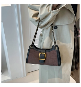Detail of suede baguette bag featuring golden horseshoe buckle and chain strap