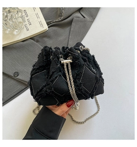 Detail of denim bucket bag showing diamond quilted stitching and pearl drawstring accent