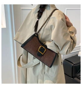 Detail of vintage baguette bag with gold buckle and chain strap on beige coat