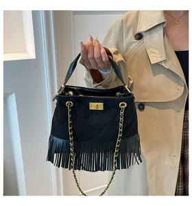 Detail of black suede bag with diamond stitching, gold lock, and long fringe tassels