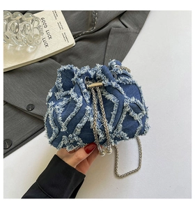 Detail of blue denim bucket bag with frayed quilted texture, drawstring and pearl charms