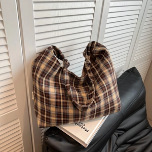 Détail du sac cabas en toile à carreaux marron avec poignée nouée à la main et étiquette tissée