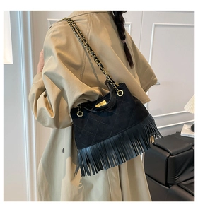 Detail view of black suede tassel bag featuring quilted pattern and gold chain strap