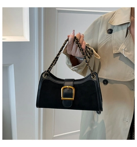 Detail of vintage black shoulder bag featuring large gold buckle and chain strap