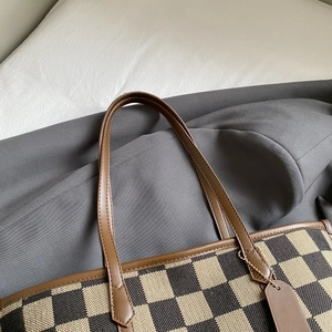 Detailed macro view of checkerboard canvas tote bag with premium leather straps
