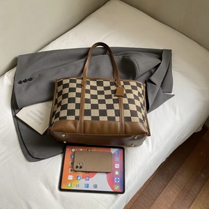 Close-up of checkerboard canvas tote with bottom metal studs and leather details
