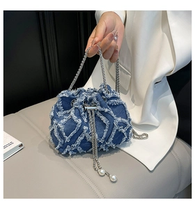 Detail of blue denim bucket bag with frayed quilted patterns and pearl chain drawstring