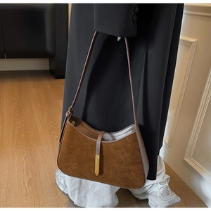Nahaufnahme der braunen Wildleder-Hobo-Tasche mit elegantem Goldanhänger und feinen Nähten