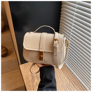 Detail of beige flap shoulder bag featuring suede patchwork and gold rotating lock