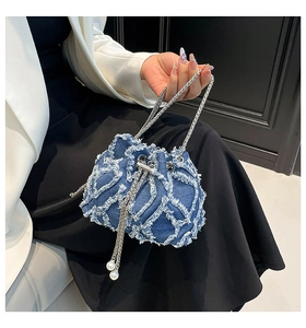 Close-up of denim bucket bag featuring frayed lattice pattern and pearl drawstring detail