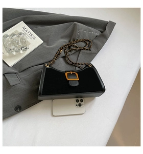 Detail of black baguette bag with gold buckle and chain, showing size next to a phone