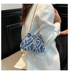 Detail of denim bucket bag with frayed fringe texture and pearl drawstring charms