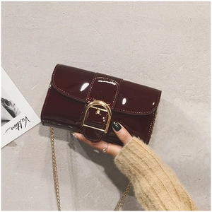 Détail du sac à main en cuir verni bordeaux avec boucle fer à cheval dorée et chaîne