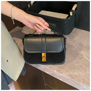 Close-up of black crossbody bag with mixed leather textures and golden twist lock