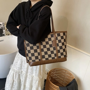 Canvas checkered tote bag with brown leather handles in a cozy lifestyle setting