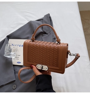 Detailed view of brown woven texture handbag with metallic twist lock and handle